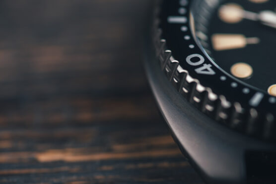 Close,Up,Of,Black,Diver,Watch,Dial.,Rustic,Wooden,Background.