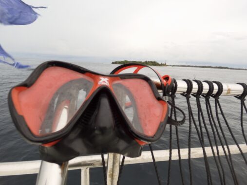 Closeup of Mares X Vision Ultra on boat rigging with flag and island in background.