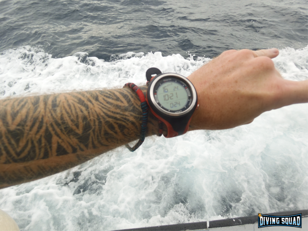 Mares Smart Air on tattooed wrist against ocean wave.