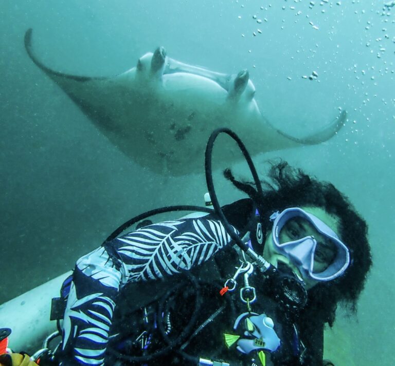 Laura diving the Maldives with manta ray behind her.