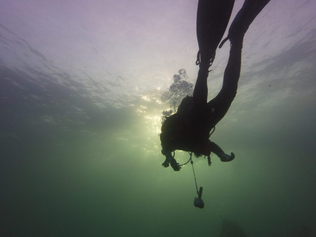 Scuba diver in the Maldives against beautiful light patterns from above.
