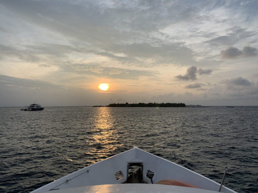 Front of Maldives Liveaboard as it heads towards island with sunset behind it.