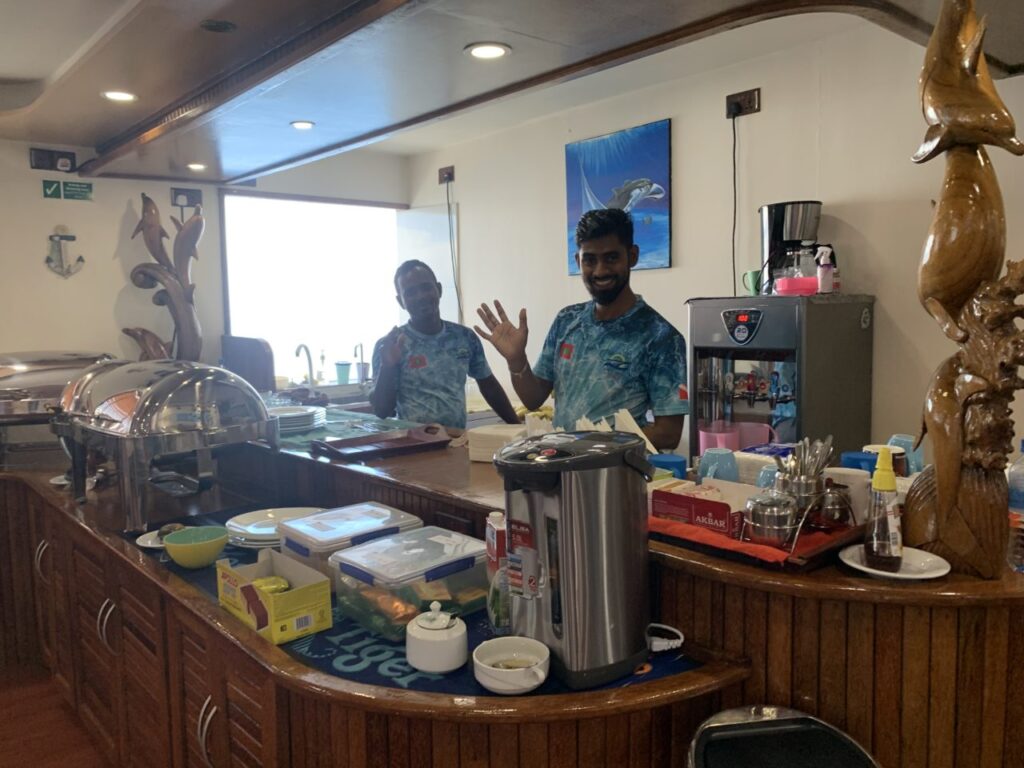 Kitchen staff serving food aboard Maldives liveaboard.