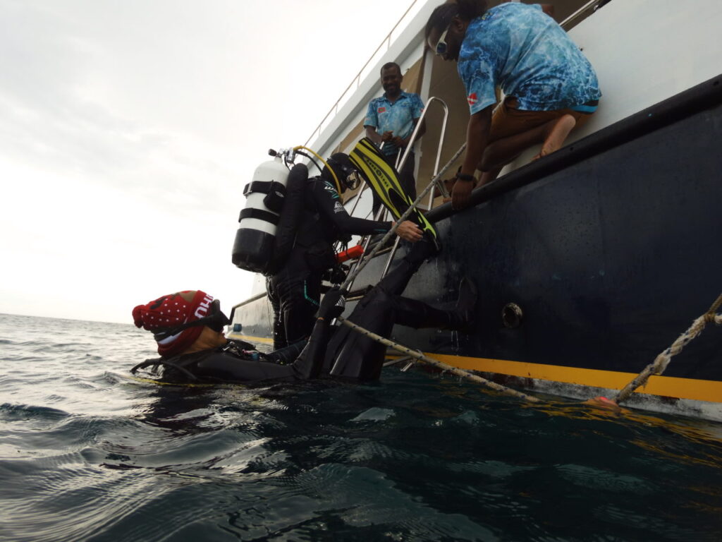 Scuba divers climbing aboard dive donny in the Maldives.