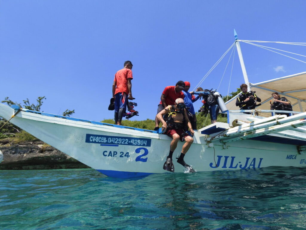 Scuba preparing to enter water from a dive boat in Moalboal.