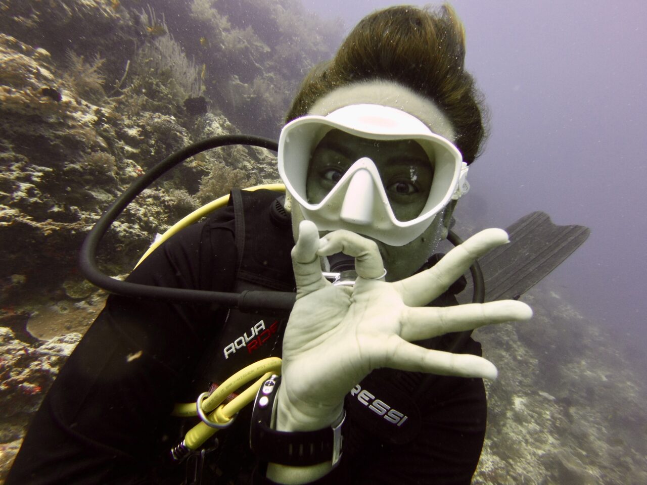 Cool scuba diving girl giving the OK sign underwater at Bohol scuba site.
