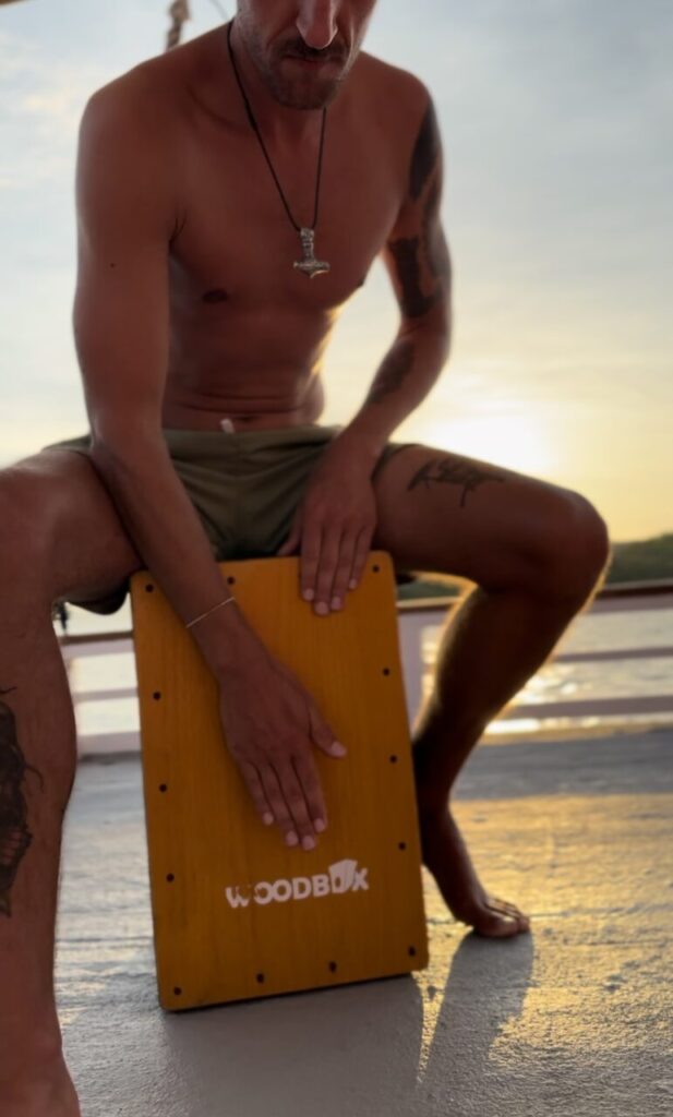 A guy playing the cajon music on the akomo isseki liveaboard