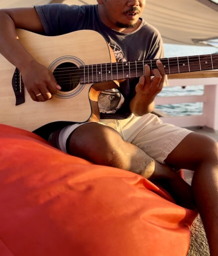 A guy playing Guitar on the akomo isseki liveaboard