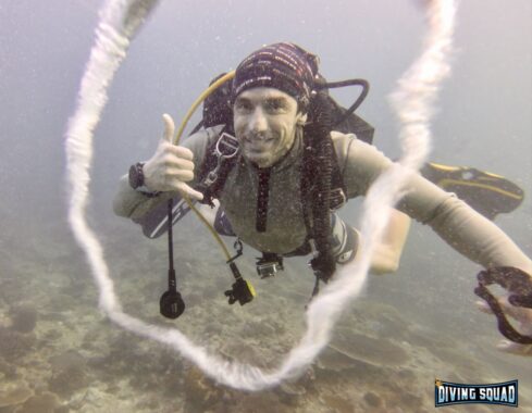 Scuba diver wearing garmin descent mk2i dive computer and blowing bubble ring.