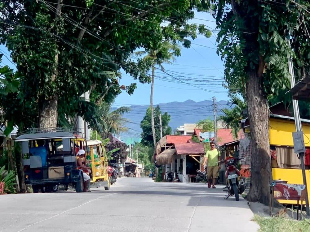 Main highstreet of Moalboal with traffic and mountains in distance.