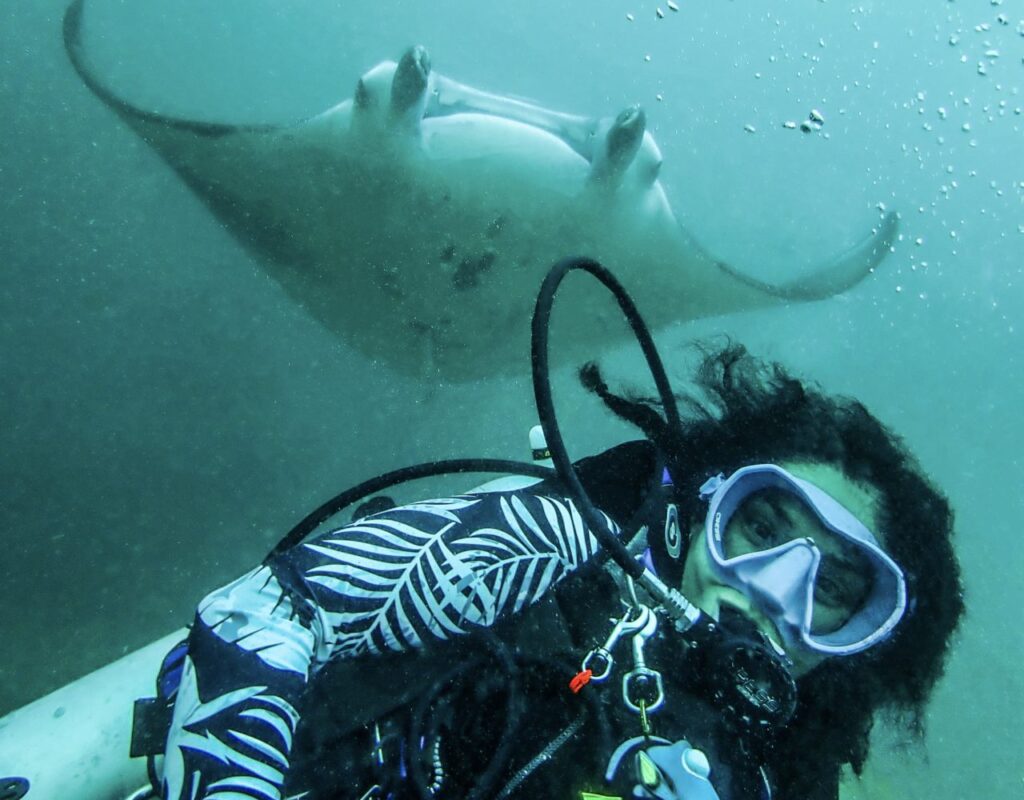 Laura diving the Maldives with manta ray behind her.